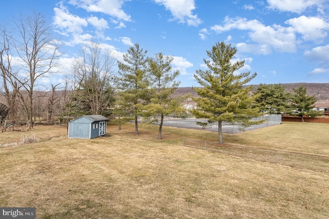 view of yard featuring a storage unit, an outdoor structure, and fence