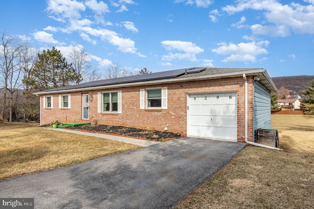 ranch-style house with aphalt driveway, an attached garage, a front yard, brick siding, and solar panels