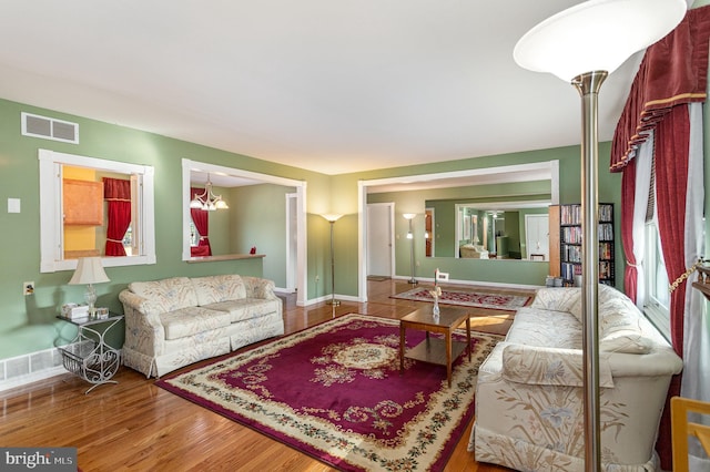 living area with wood finished floors, visible vents, and baseboards