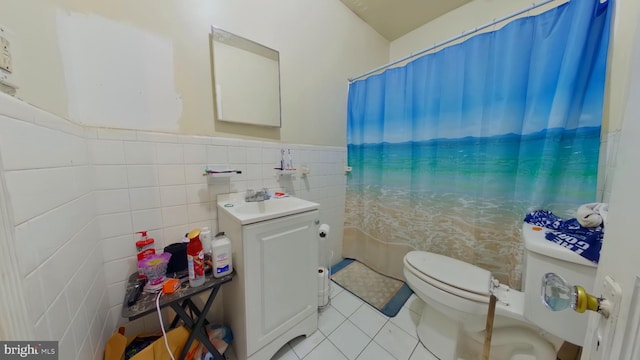 full bath with vanity, tile patterned flooring, toilet, wainscoting, and tile walls