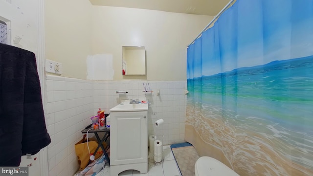 full bath with vanity, a wainscoted wall, toilet, tile walls, and tile patterned floors