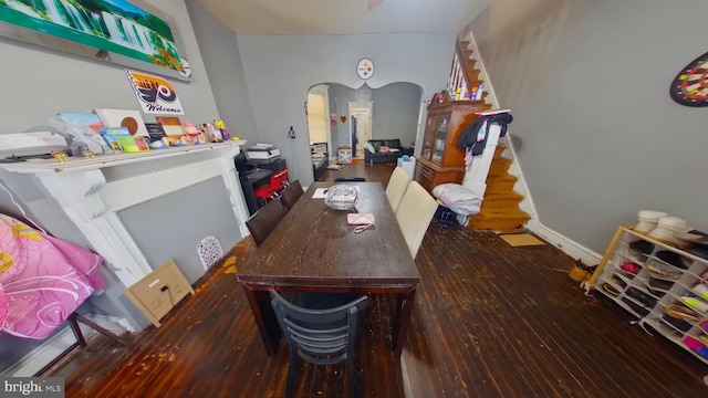 dining area with arched walkways and wood finished floors