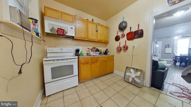 kitchen with baseboards, white appliances, light tile patterned floors, light countertops, and arched walkways