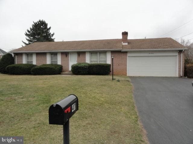 ranch-style home with a front yard, driveway, a chimney, a garage, and brick siding