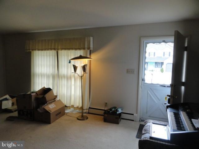 living room featuring a baseboard heating unit and carpet