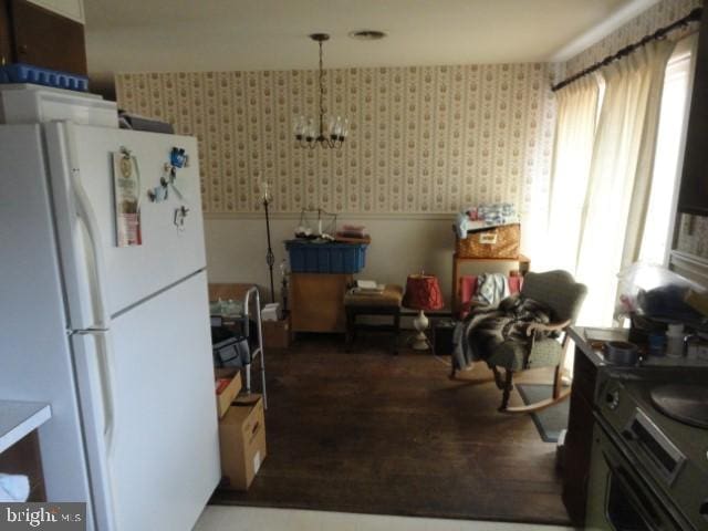 kitchen with wainscoting, wallpapered walls, freestanding refrigerator, and wood finished floors