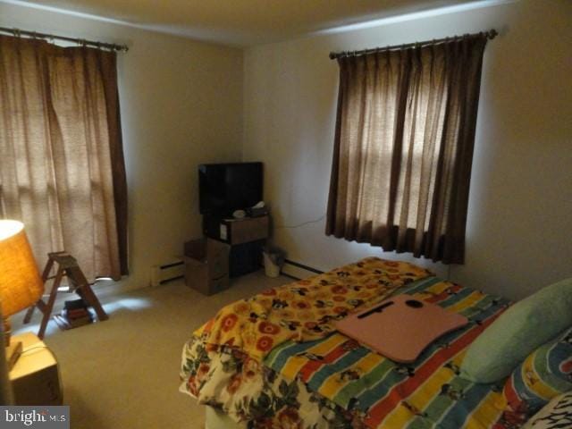 carpeted bedroom with a baseboard heating unit and multiple windows