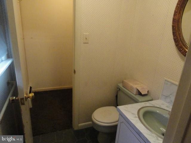 bathroom with baseboards, toilet, and vanity