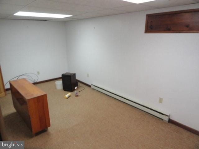 finished below grade area with carpet flooring, a paneled ceiling, baseboards, and a baseboard radiator