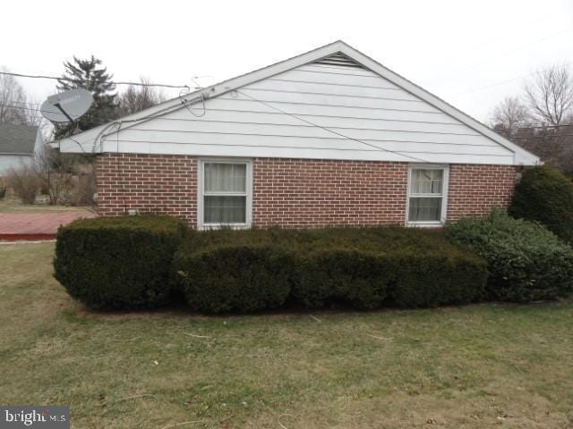 view of side of property with a yard and brick siding