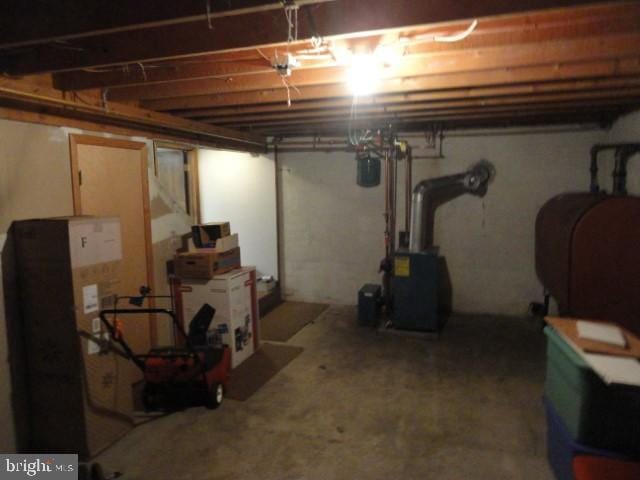 unfinished below grade area with a heating unit and heating fuel