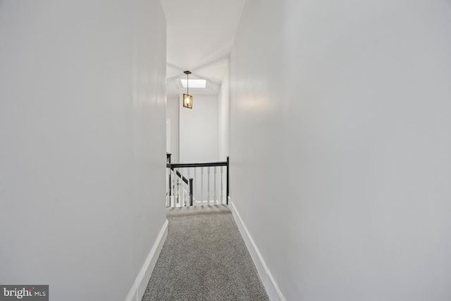 hallway with an upstairs landing, baseboards, and carpet floors