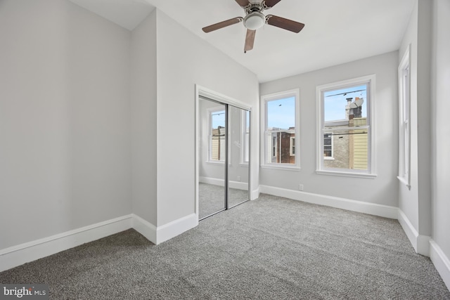 unfurnished bedroom with baseboards, multiple windows, carpet floors, and a closet