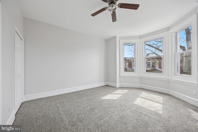 carpeted spare room with a ceiling fan and baseboards