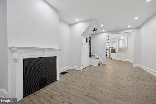 unfurnished living room featuring wood finished floors, visible vents, baseboards, a fireplace, and recessed lighting