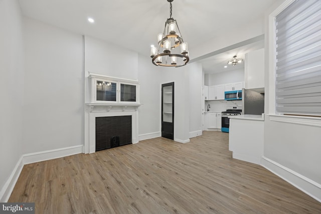 unfurnished living room featuring light wood-style flooring, recessed lighting, baseboards, and a large fireplace