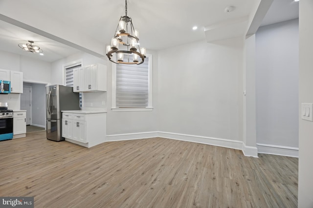 kitchen featuring light wood-type flooring, white cabinetry, stainless steel appliances, light countertops, and baseboards