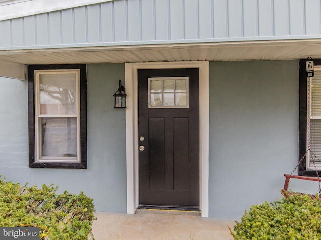 view of exterior entry featuring covered porch and board and batten siding