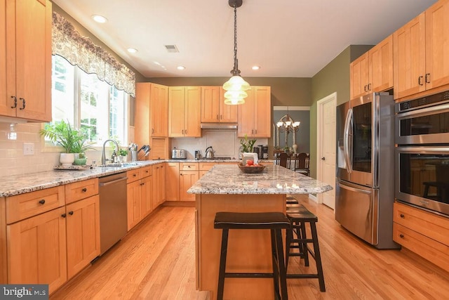 kitchen with light wood-type flooring, light brown cabinetry, a sink, a center island, and stainless steel appliances