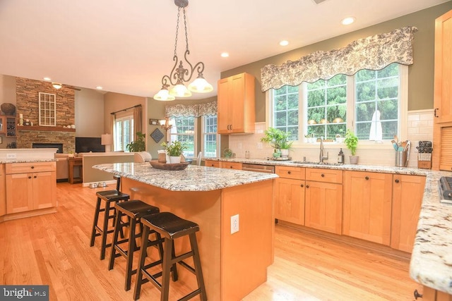 kitchen with a sink, decorative backsplash, a center island, and light brown cabinetry