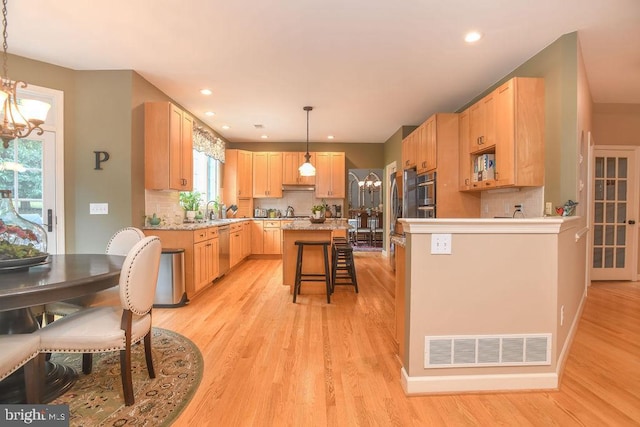 kitchen featuring visible vents, an inviting chandelier, light wood-style flooring, and appliances with stainless steel finishes