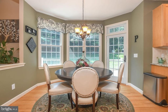 dining space with light wood-style flooring, a notable chandelier, and plenty of natural light