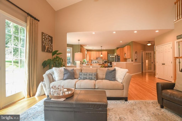 living room featuring a wealth of natural light, recessed lighting, high vaulted ceiling, and light wood-style floors