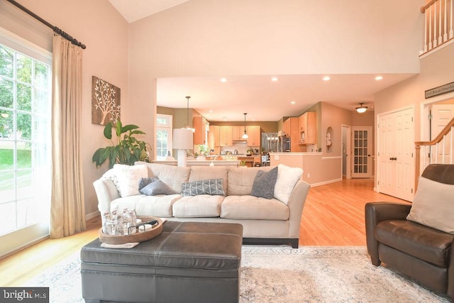 living room with recessed lighting, light wood-style flooring, high vaulted ceiling, and baseboards