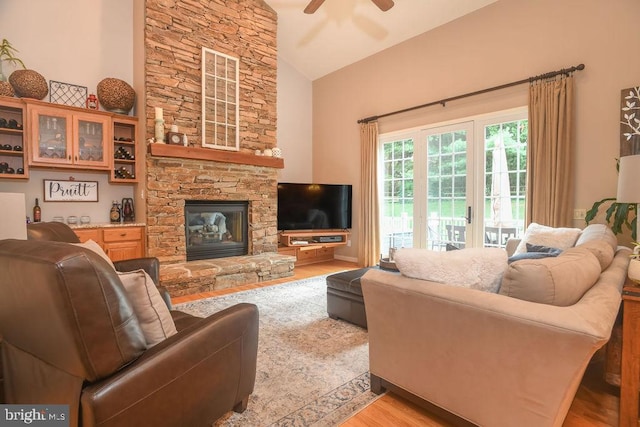 living room with light wood finished floors, a fireplace, high vaulted ceiling, and ceiling fan