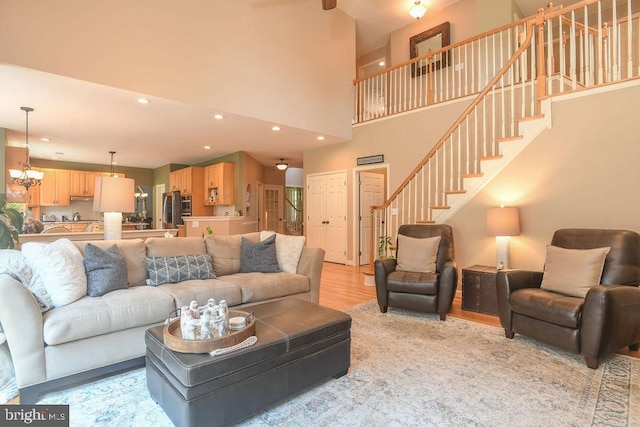 living area featuring a notable chandelier, recessed lighting, stairway, a high ceiling, and light wood finished floors