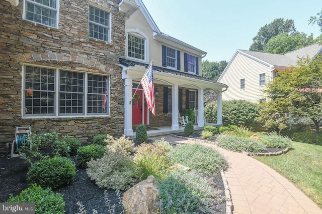 view of front of house with stucco siding, stone siding, and covered porch