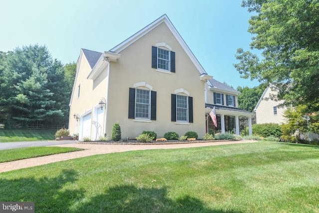 view of front facade with stucco siding, driveway, a front lawn, and a garage