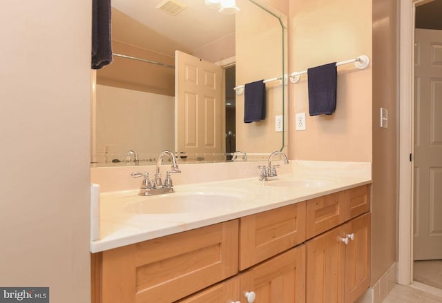 full bath featuring a sink, visible vents, double vanity, and tile patterned flooring