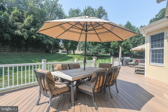 wooden deck featuring outdoor dining area, fence, and a yard