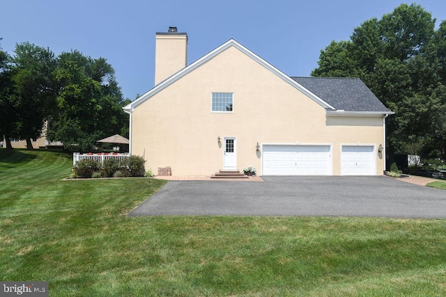 view of side of property featuring stucco siding, driveway, a yard, an attached garage, and a chimney