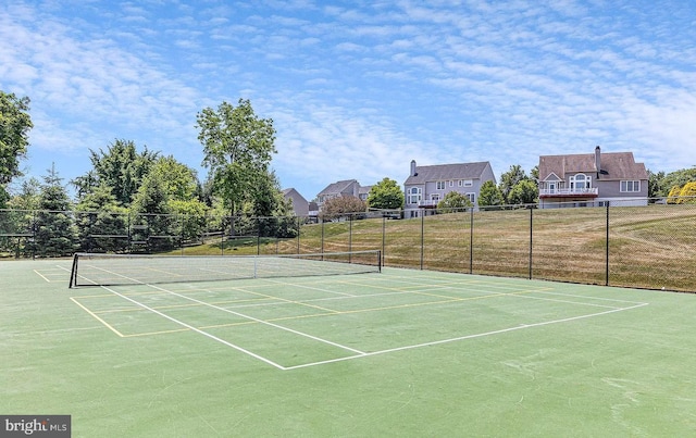 view of tennis court with community basketball court and fence