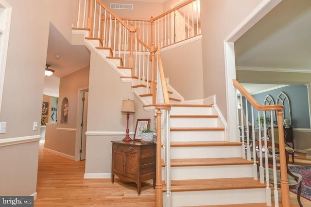 stairs with visible vents, crown molding, baseboards, and wood finished floors