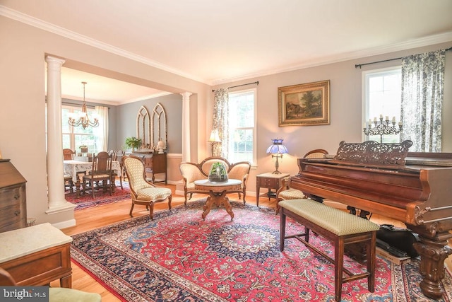 living area featuring an inviting chandelier, decorative columns, plenty of natural light, and light wood finished floors