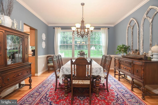 dining space with light wood-style flooring, ornamental molding, baseboards, and a chandelier