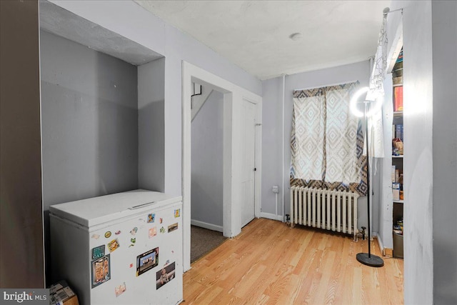 interior space with radiator heating unit, wood finished floors, and baseboards