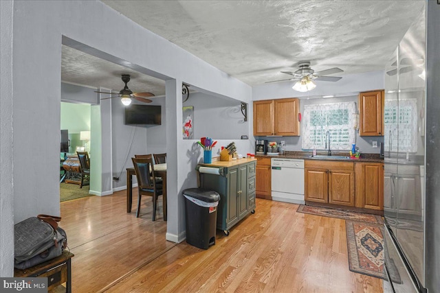 kitchen featuring a sink, light wood-type flooring, a textured ceiling, and dishwasher