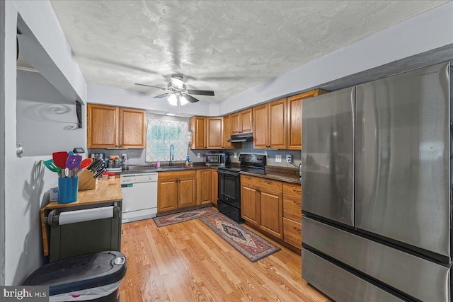 kitchen featuring a sink, under cabinet range hood, freestanding refrigerator, black / electric stove, and dishwasher