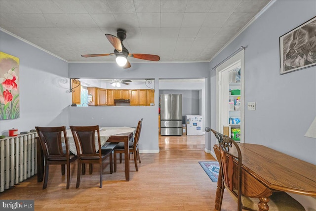 dining room featuring crown molding, a ceiling fan, light wood-type flooring, and baseboards