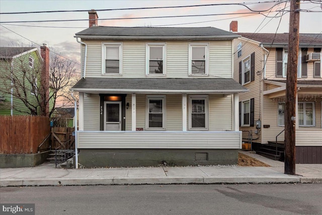 view of front of house featuring covered porch, a chimney, and fence