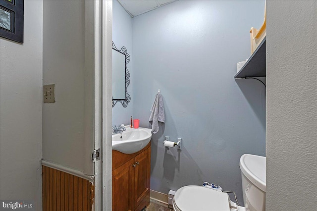 half bathroom featuring vanity, toilet, and baseboards