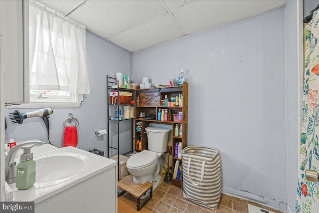 full bathroom featuring a paneled ceiling, toilet, and vanity