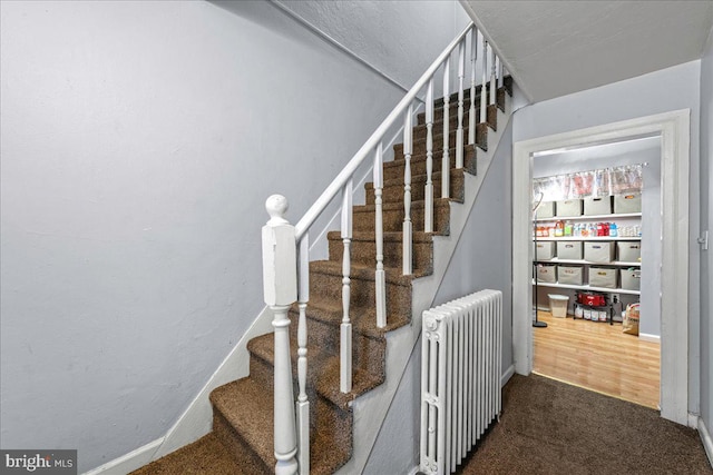 stairway with carpet flooring, baseboards, and radiator heating unit