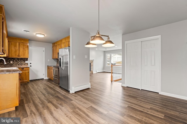 kitchen with baseboard heating, brown cabinets, decorative backsplash, dark wood-style floors, and stainless steel appliances