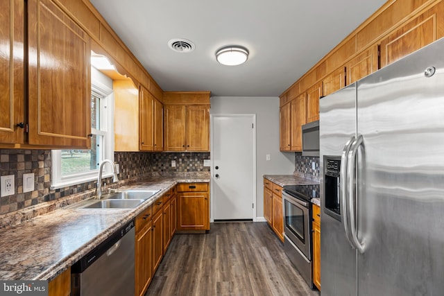 kitchen with brown cabinetry, visible vents, stainless steel appliances, and a sink