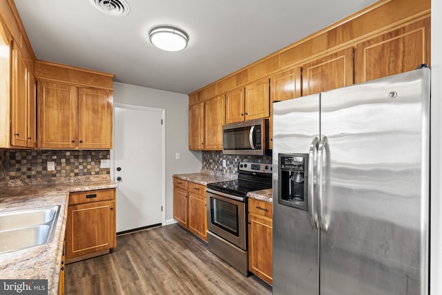 kitchen featuring visible vents, brown cabinets, stainless steel appliances, and dark wood-style flooring